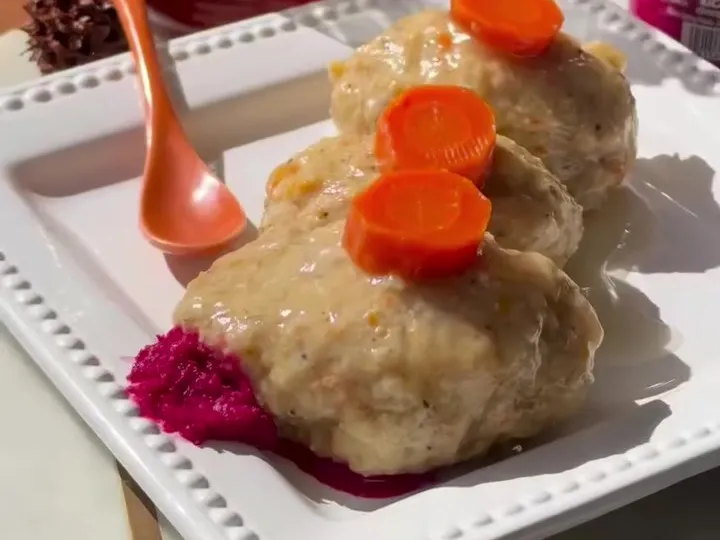 Gefilte fish patties topped with carrot slices on a white plate