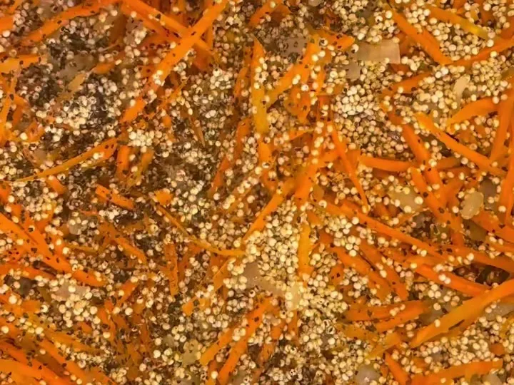 Quinoa with shredded carrots cooking in a pan