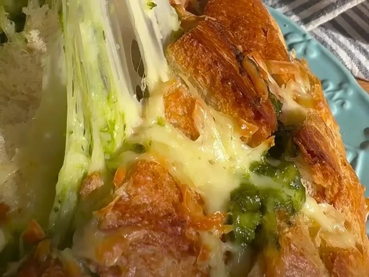 Pull-apart bread stuffed with pesto and melted mozzarella, with a long cheese pull