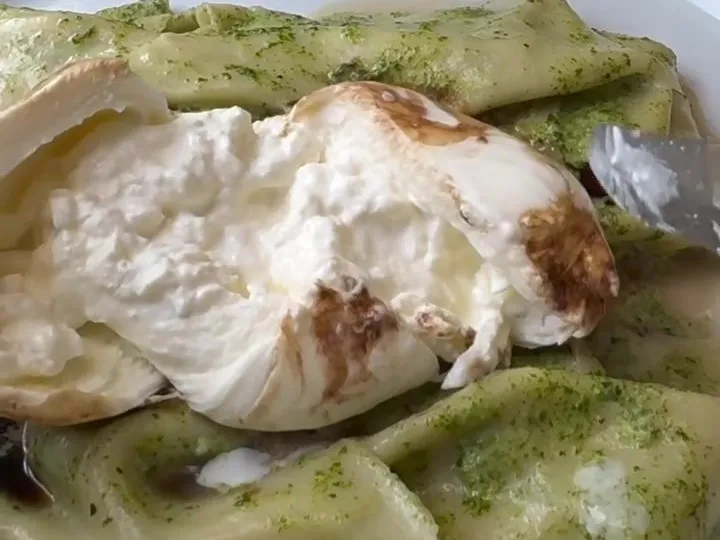 Green basil pasta topped with torn burrata and a drizzle of balsamic
