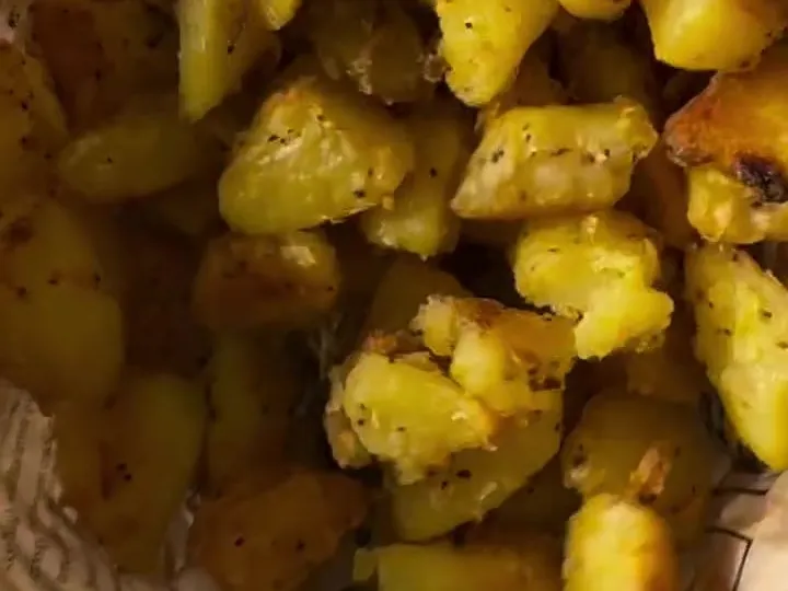 Crispy roasted potato cubes with herbs in a paper-lined basket