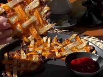 A crispy woven lattice of white and sweet potato strips held over a plate with dip