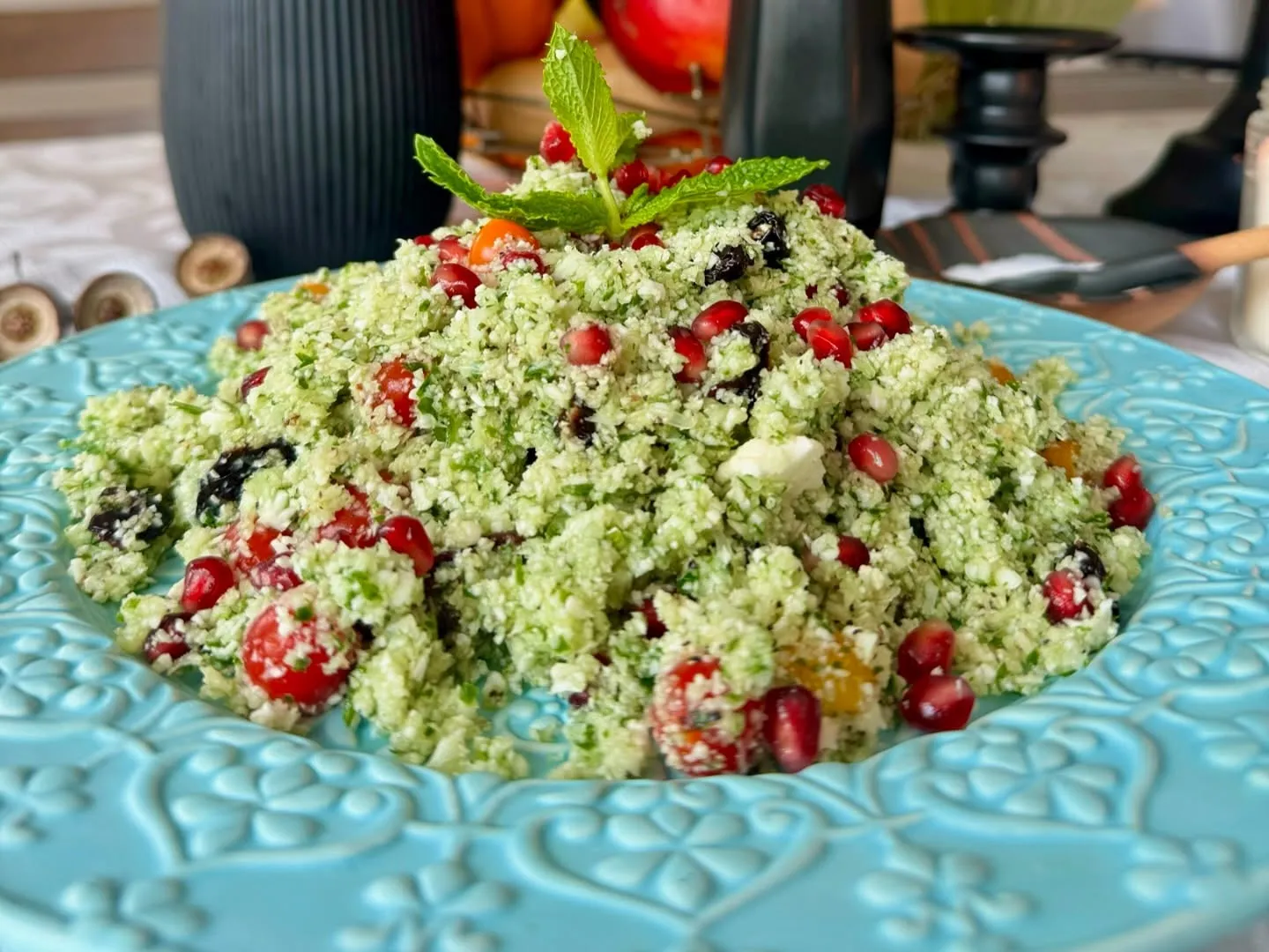 Cauliflower tabouli salad with herbs and pomegranate seeds on a turquoise plate