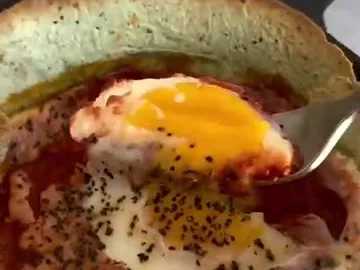 Spinach tortilla baked in a small pan with tomato sauce and an egg