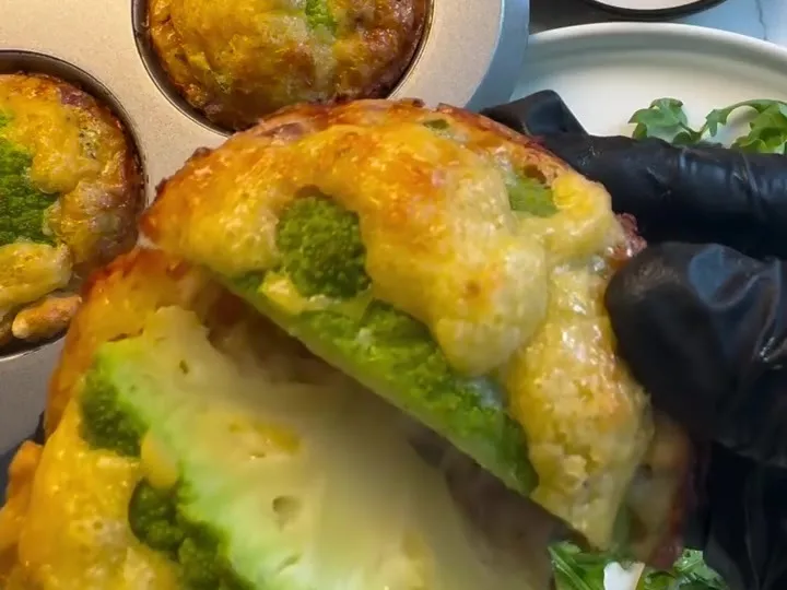 A cheesy muffin cut in half to show a green cauliflower floret inside