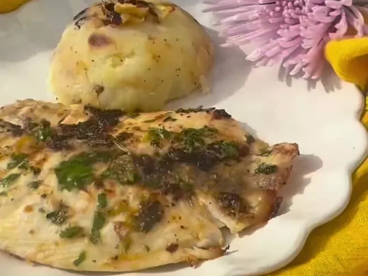 Grilled white fish fillet with herbs next to a scoop of mashed potatoes