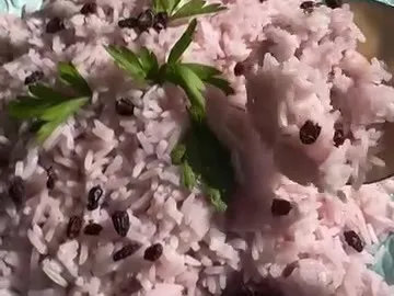 Pink-purple rice with dried berries and parsley on a turquoise plate