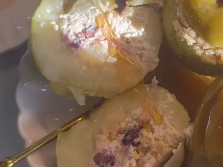 Baked apples filled with cheese filling, with cinnamon stick stems and a honey drizzle